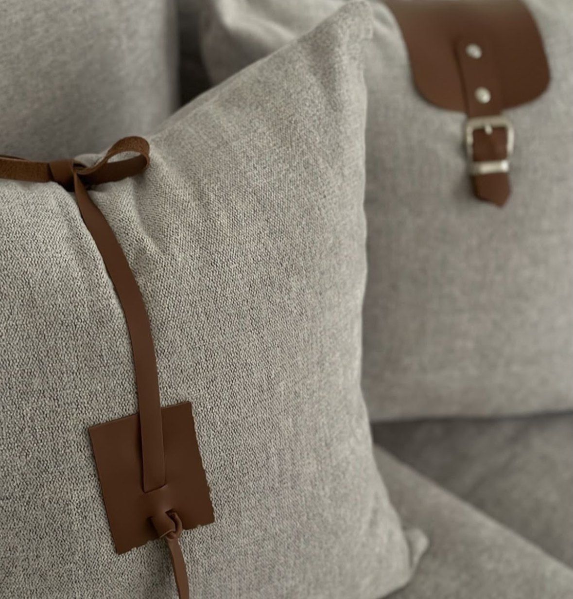Almohadones grises con detalles de cuero, moño y hebilla